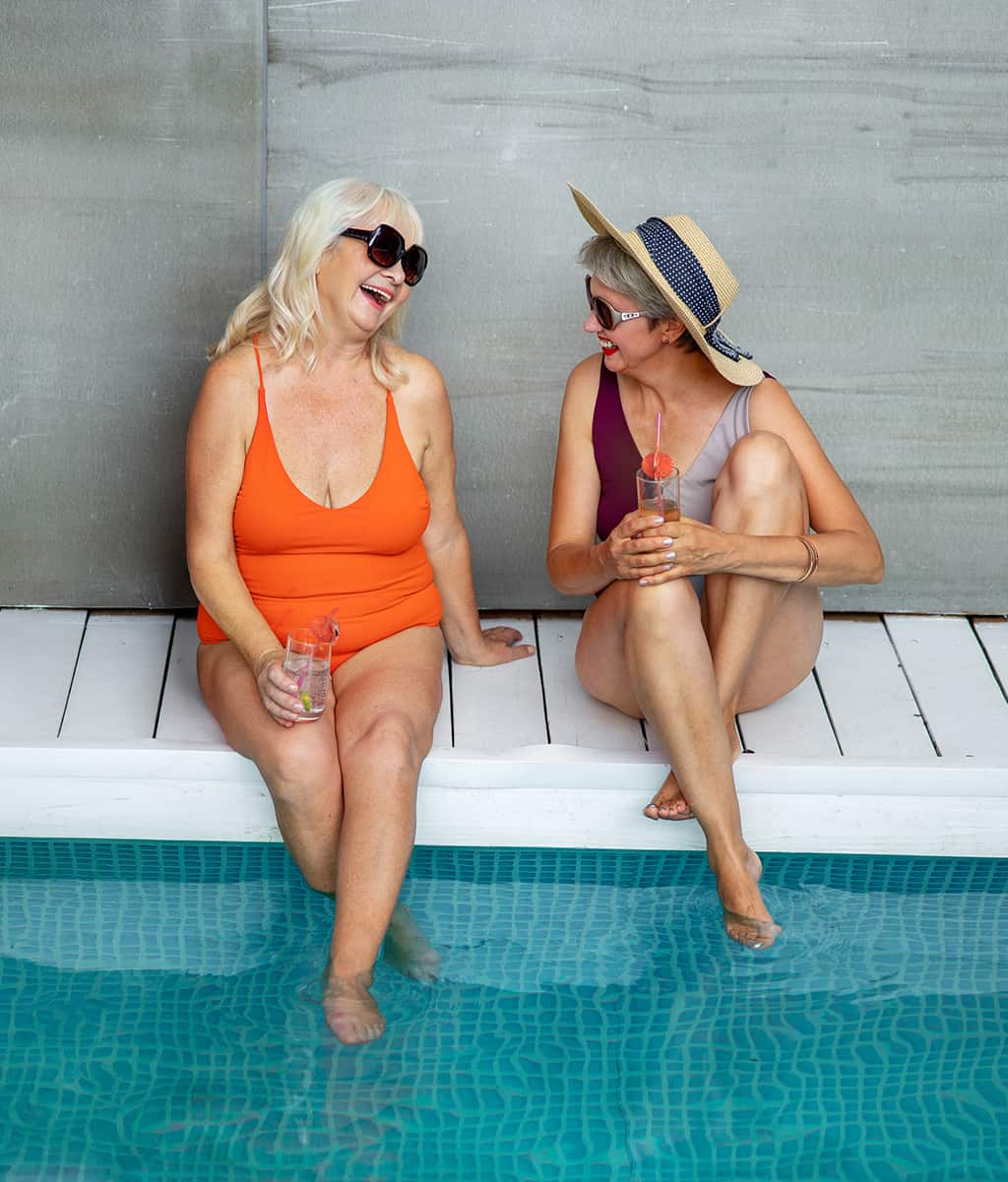 Lifestyle pool image with two friends hanging by the pool